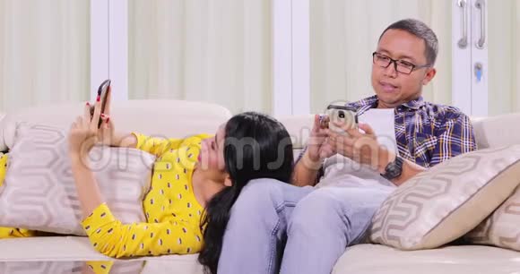 夫妻俩在沙发上用自己的手机视频的预览图