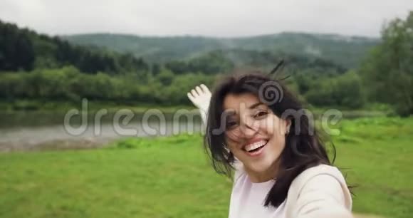 布鲁内特年轻女性制作故事自拍在河边的山上展示风景印象深刻开心视频的预览图