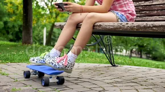 把女孩的双脚放在一个坐在长凳上的溜冰鞋上视频的预览图