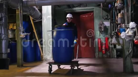 一个制造工厂的男工程师用桶卷一辆手推车视频的预览图