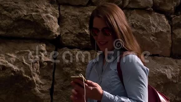 美丽的年轻女子站在石墙前视频的预览图