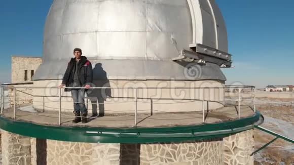一位成年男性天文台工作人员站在观察穹顶的观察甲板上向远处望去视频的预览图