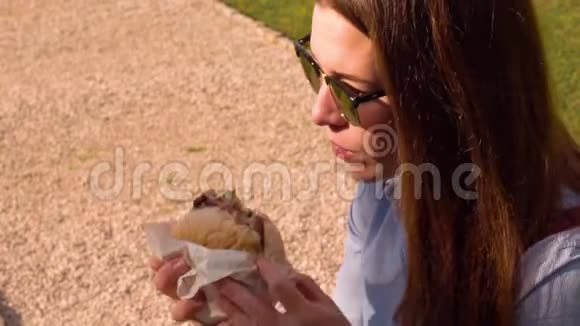 戴太阳镜的女人吃汉堡包视频的预览图