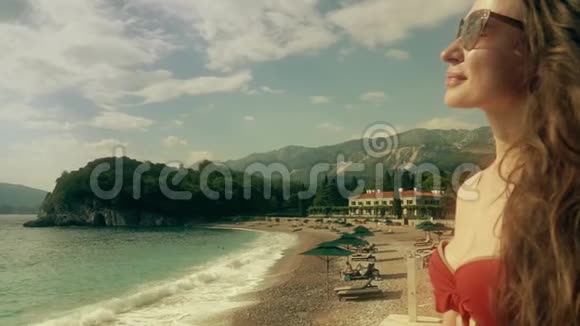 美丽的年轻女子穿着红色比基尼在海滩上日光浴视频的预览图