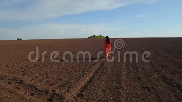 穿着红色长裙在犁地奔跑的欢乐女人空中射击视频的预览图