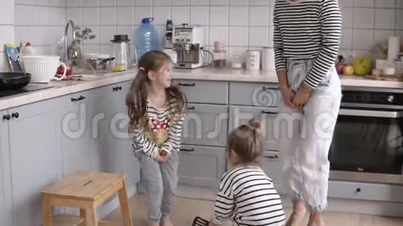 有趣年轻开朗的妈妈正在和女儿们玩耍在厨房里用铲子模仿骑马视频的预览图
