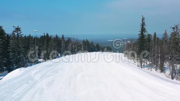 冬天人们在滑雪坡上看到美丽的景色开始沿着针叶树附近的一条小径向蓝色行进视频的预览图