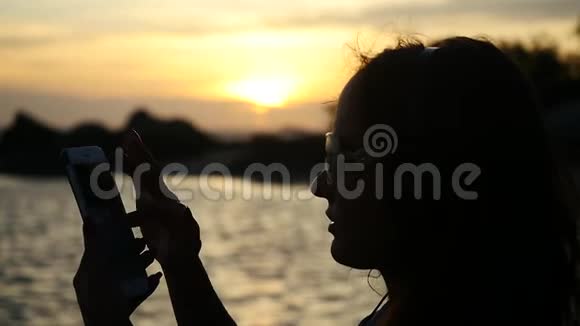 年轻女性在阳光下使用手机的剪影慢动作1920x1080视频的预览图