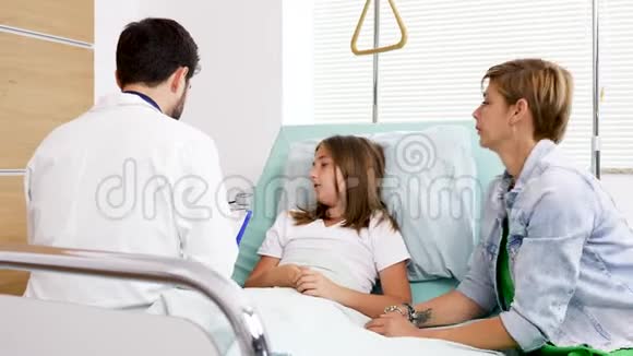 医生坐在医院的病床上询问少女的健康问题视频的预览图