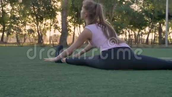 年轻漂亮的女人坐在公园的足球场上晨练健身模特锻炼视频的预览图