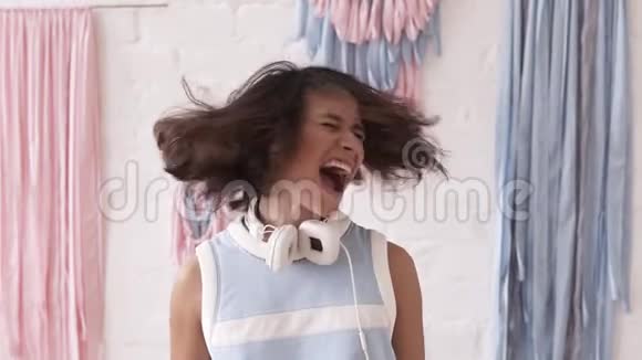 一个年轻的黑发女孩玩得很开心摇了摇头大喊大叫的慢镜头印度支视频的预览图