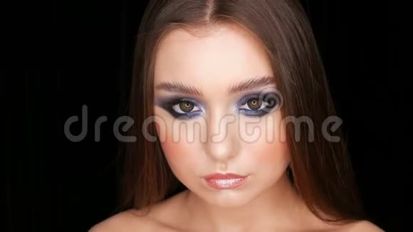 美丽性感的年轻女孩晚上蓝色化妆烟雾般的眼睛长发和化妆色隐形眼镜摆姿势视频的预览图