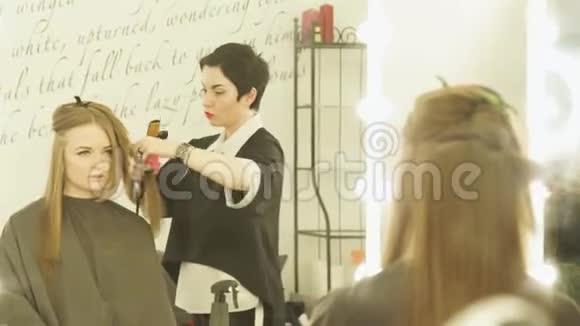 美容师用发钳制作发型并在美容院梳头贴身女理发师视频的预览图