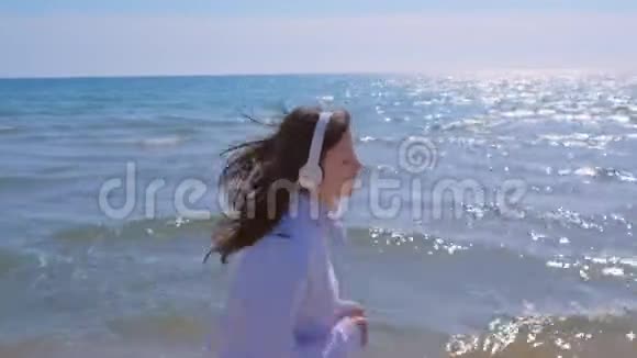 女士戴耳机音乐慢跑在海沙滩运动跑步户外训练视频的预览图