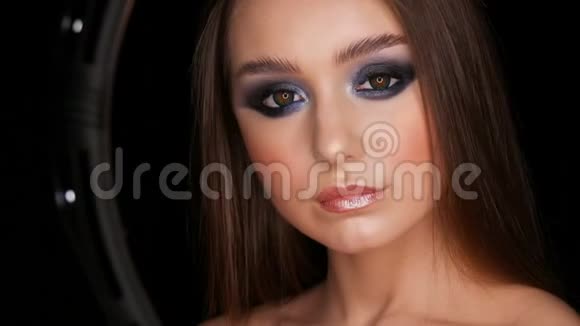美丽性感的年轻女孩晚上蓝色化妆烟雾般的眼睛长发和化妆色隐形眼镜摆姿势视频的预览图