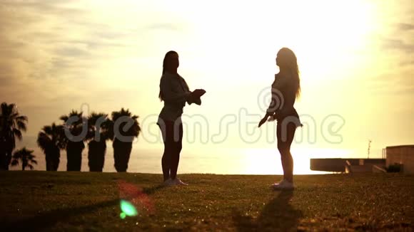 快乐的姐妹或朋友在沙滩上享受日落视频的预览图