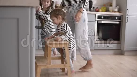年轻时尚的母亲帮助女儿用铲子翻煎饼在厨房一起做饭时玩得很开心视频的预览图