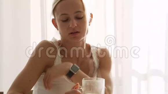 女人慢慢地在透明的玻璃杯里倒热凉茶在家吃健康早餐视频的预览图