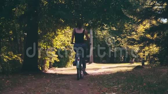 在夏日阳光明媚的日子里少女在绿树丛中骑自行车视频的预览图