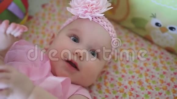 小女婴躺在床上玩耍穿着粉红色的裙子视频的预览图