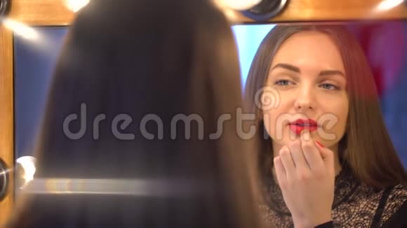 一个年轻漂亮的女人正在化妆照镜子一个女人在涂红唇膏视频的预览图