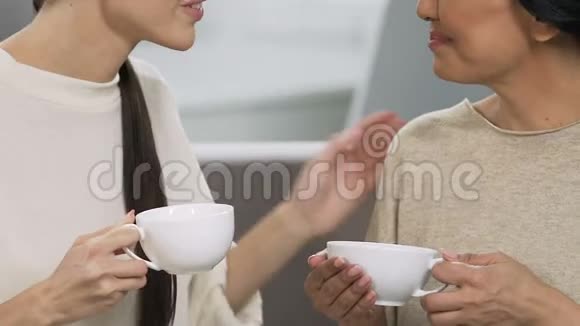 成年姐妹微笑着用茶杯交谈家庭放松气氛支持视频的预览图
