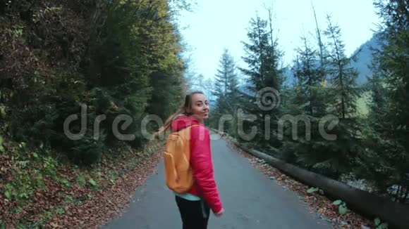 女徒步旅行者带着小背包走在森林里的路上视频的预览图