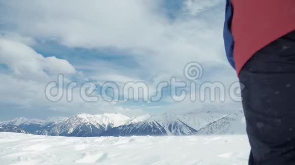 男子背着背包站在雪山顶上胜利者摆姿势举起双手欣赏风景和成就视频的预览图