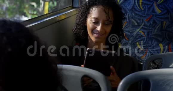 母亲和女儿在乘坐4k公共汽车时使用数字平板电脑视频的预览图