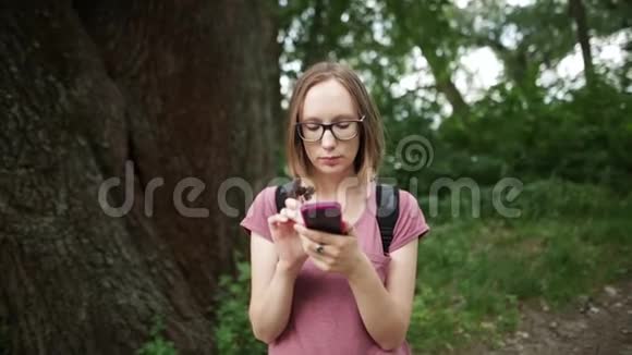 戴眼镜的女孩和她的智能手机聊天头发随风飘扬视频的预览图