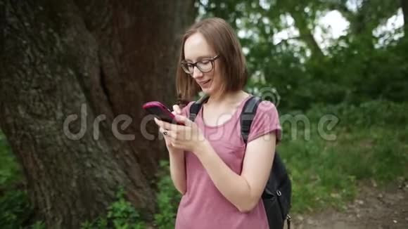 戴眼镜的女人和她的智能手机聊天头发随风飘扬视频的预览图
