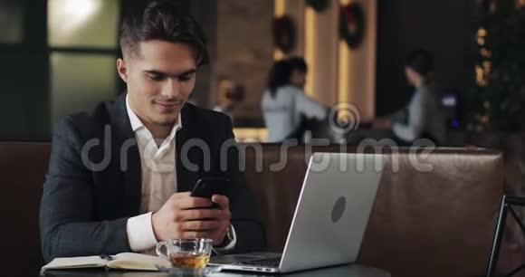 在咖啡馆工作的年轻商人使用智能手机和笔记本电脑的自由职业者成功的职业生涯IT自由职业者的概念视频的预览图