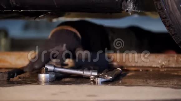 汽车服务厚厚的机械师躺在车下用手寻找工具带着一个钳子视频的预览图