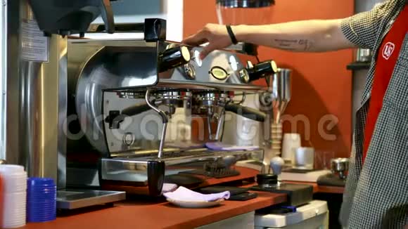 咖啡厅专业咖啡机的咖啡师艺术咖啡师在做杯子之前先清洗和擦拭浓缩咖啡机视频的预览图