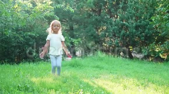 可爱的小女孩在绿色的夏天公园里跳杰克视频的预览图