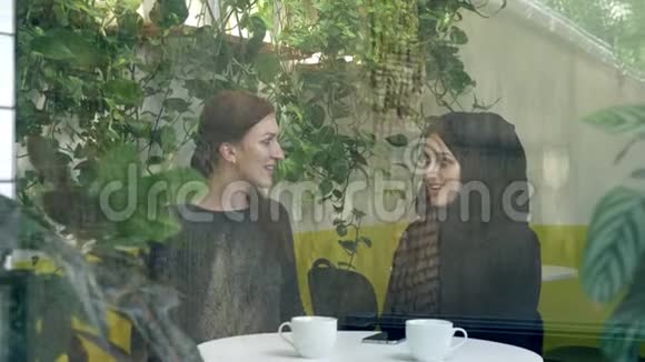 两个年轻的女人坐在咖啡馆里其中一个是戴着头巾的穆斯林女人在外面谈笑风生视频的预览图