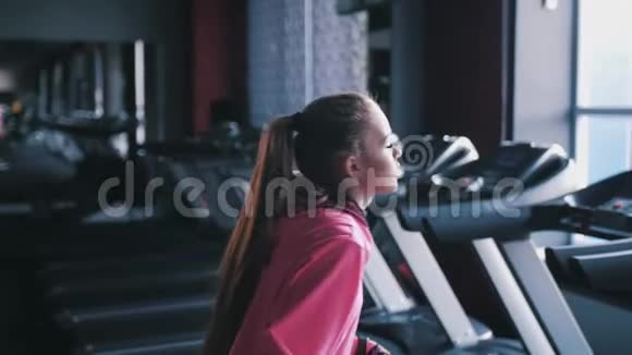 一个漂亮的高加索女人在跑步机上的健身房里跑步视频的预览图