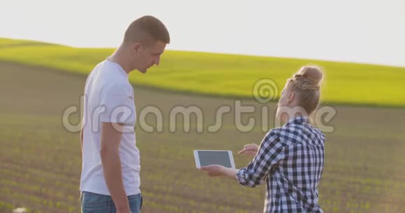 农场上的一对夫妇在绿色植物领域交谈视频的预览图
