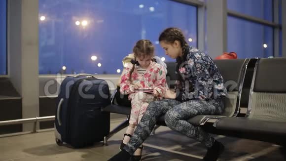 两个疲惫的女孩晚上在机场等你的航班视频的预览图