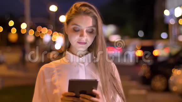 年轻漂亮的女孩在夏天的晚上在她的平板电脑上打字思维观念沟通观念视频的预览图