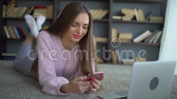 这个学生女孩在家里的电脑背景上使用手机4千克视频的预览图