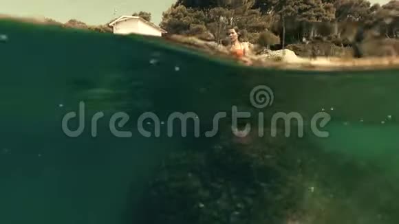一位美丽的年轻女子潜入大海在水上射击视频的预览图