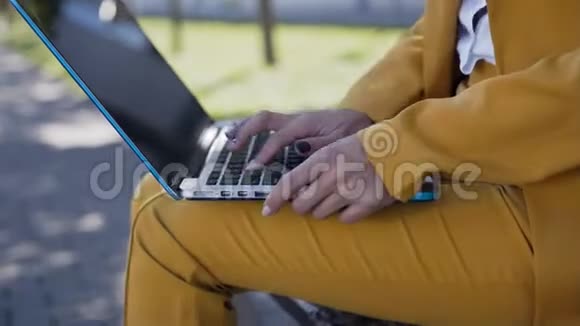 女性在电脑键盘上打字的特写镜头在户外穿着西装的年轻女商人坐在长凳上视频的预览图
