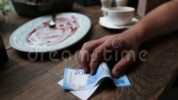 在咖啡馆付现金的人纸币在人手餐厅支票在木桌上视频的预览图