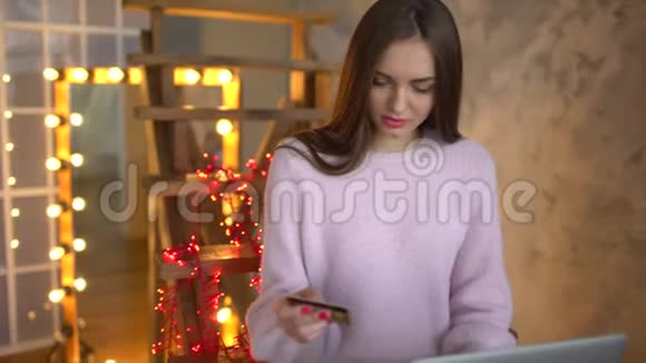 年轻漂亮的少女使用她的信用卡和笔记本电脑在网上购物女子在网上购物视频的预览图