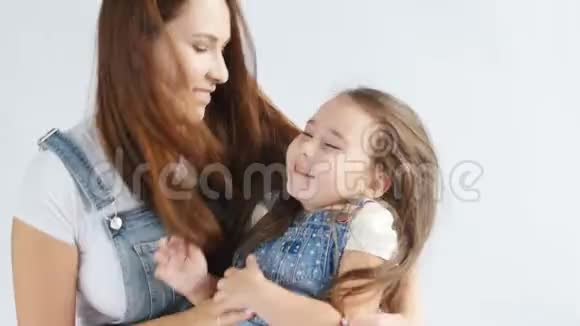 妈妈高兴地把可爱的女儿的头发梳在白色的内部视频的预览图