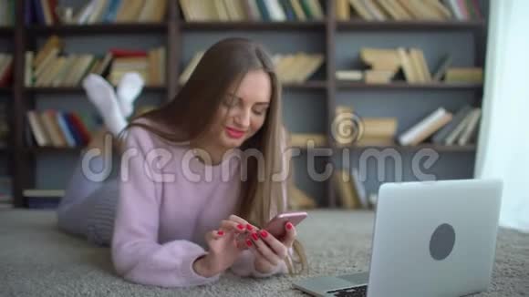 这位年轻女子在图书馆的电脑背景上使用手机4千克视频的预览图