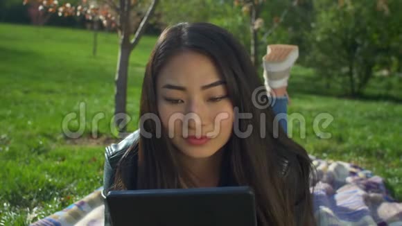 春天公园有平板电脑的迷人亚洲女孩视频的预览图