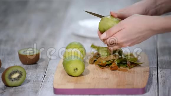 一个女人用一把刀在木头背景上清洗猕猴桃皮视频的预览图