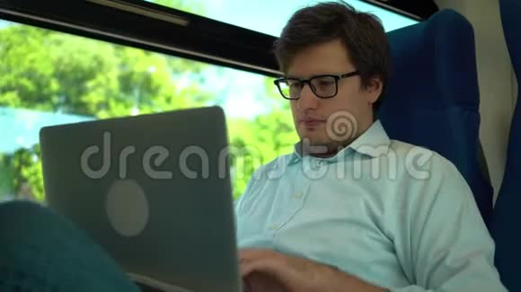 年轻商人在火车上拿着笔记本电脑工作微笑着视频的预览图